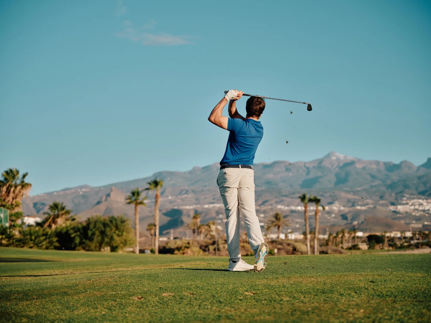 Golfer playing a tee shot at Amarilla Golf with mountains behind the course